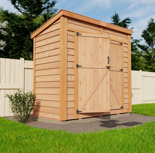An 8x4 Outdoor Living Today GardenSaver with single door, made of natural wood, is situated in a lush green garden against a backdrop of a wooden fence and tall trees.