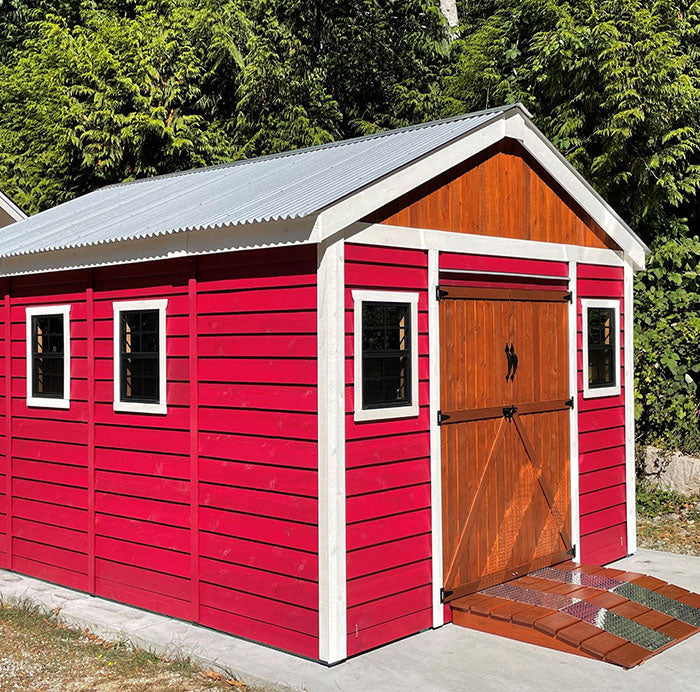 Painted red and white Outdoor Living Today Space Master Wooden Storage Shed 12x16  with metal roof and ramp on a cement floor