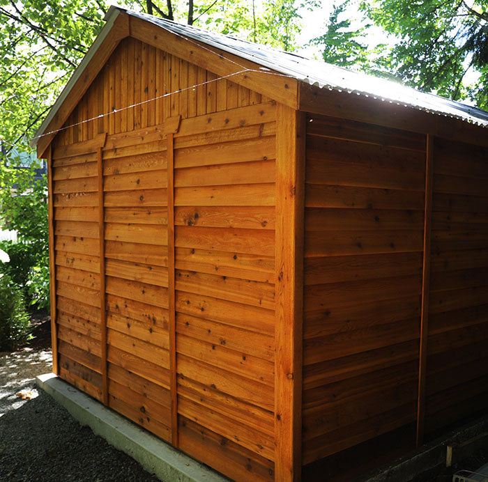 Rear view of the Outdoor Living Today Space Master Wooden Storage Shed 12x16  on a cement pad