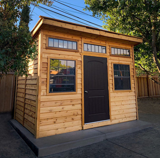 Outdoor Living Today Studio 12x8 shed situated in a backyard with natural surroundings
