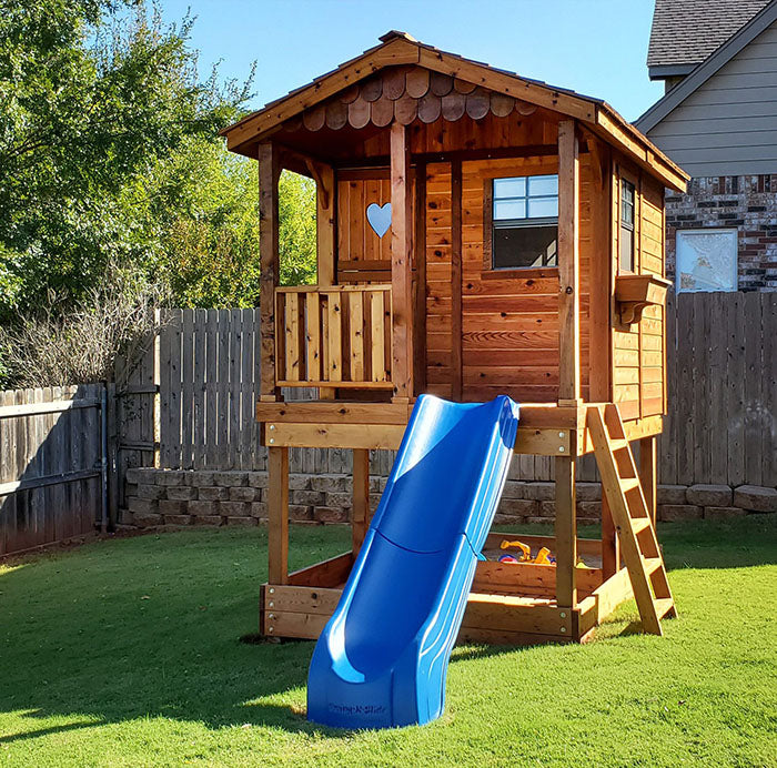 Outdoor Living Today Sunflower Playhouse elevated on stilts, complete with a playful blue slide and heart-shaped window detail.