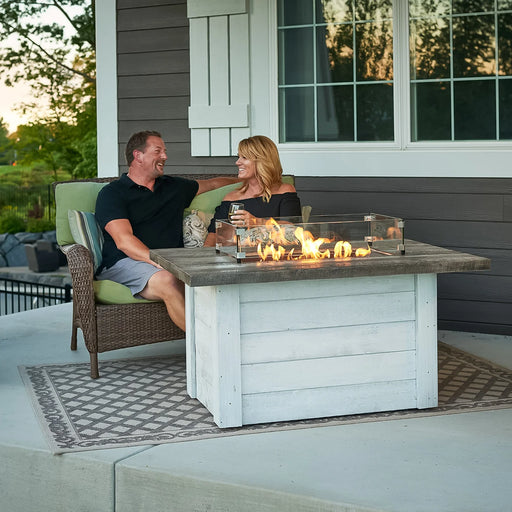 Lifestyle image of the Alcott Rectangular Gas Fire Pit Table being used by two people, showcasing the product in a social setting.
