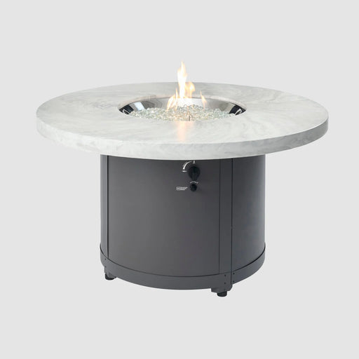 Side view of Outdoor Greatroom Co Beacon Round Gas Fire Pit Table in White Onyx, with a bright flame at the center, SKU BC-20-WO.
