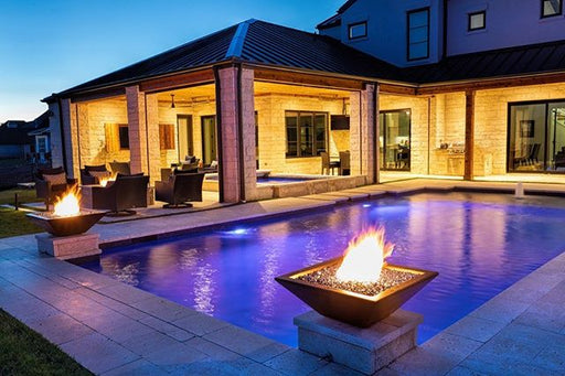 Elegant backyard at dusk featuring a square GFRC fire bowl with a vivid fire adding warmth to the outdoor living space.