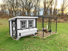 The OverEZ Chicken Coop Farmhouse Model in white with an attached secure chicken run, showcased in an outdoor setting at dusk.