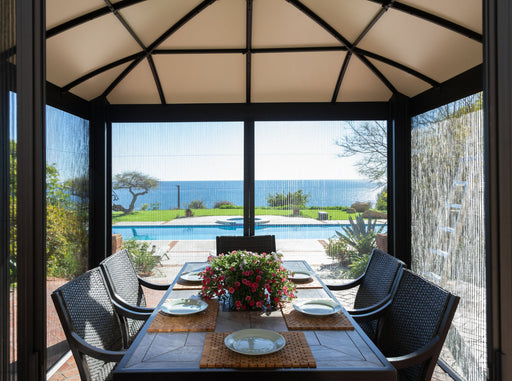 Interior design of the Siena Hard Top gazebo showing a dining setup for six, with a view of a pool and the sea, illustrating the gazebo's spacious and elegant design.