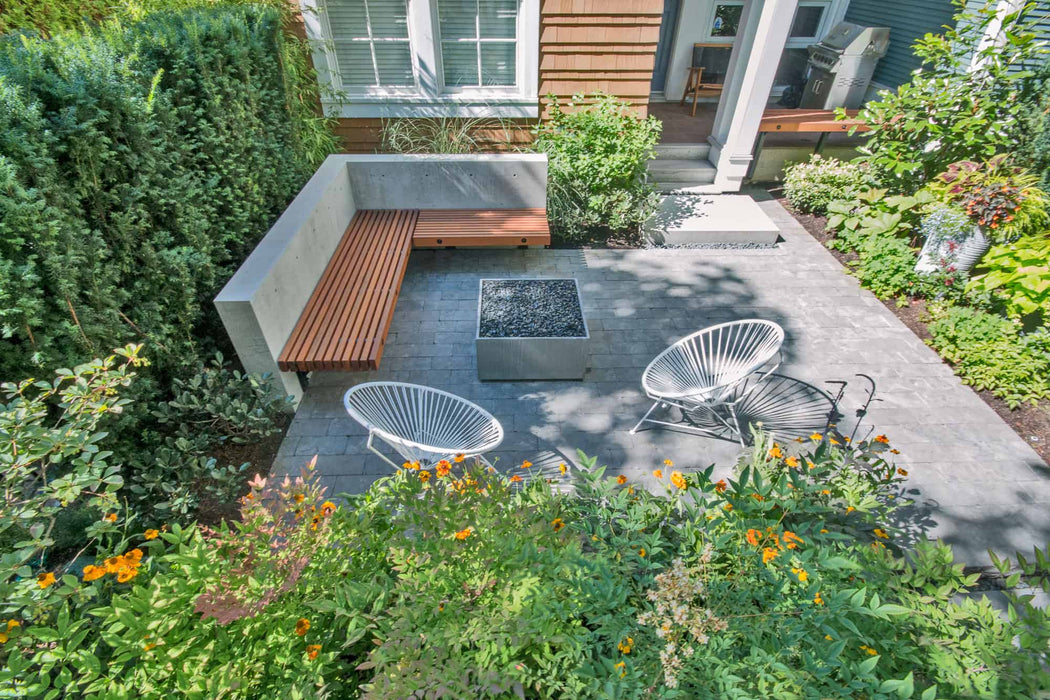 A tranquil outdoor nook graced with the Solus Decor Firebox 30, complemented by modern metal seating and natural landscaping.