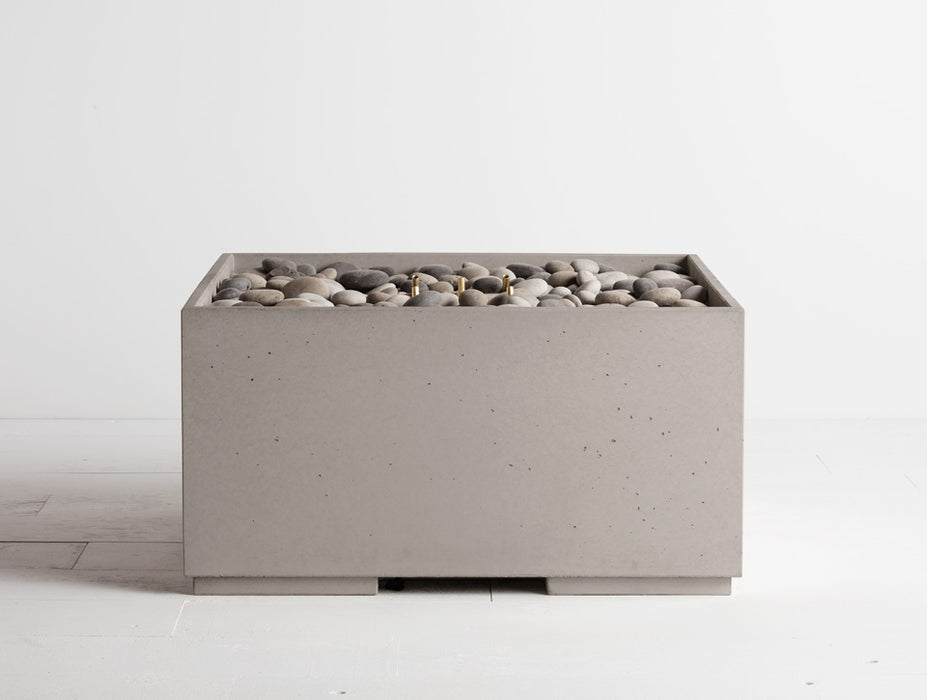 Portland grey Solus Decor Firebox 30, merging industrial chic with functional outdoor warmth, complemented by a bed of smooth pebbles.