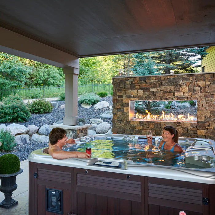 A family enjoys an outdoor gathering around the Fire Pit Table, on a patio.