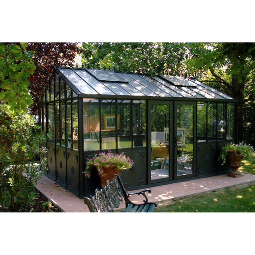 A luxurious Exaco Janssens Retro Royal Victorian VI Greenhouse nestled in a serene garden oasis, featuring a spacious interior and ornate detailing.
