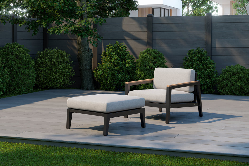 Rhodes	Chat Chair with Ottoman	in an outdoor setting with dark fence background.