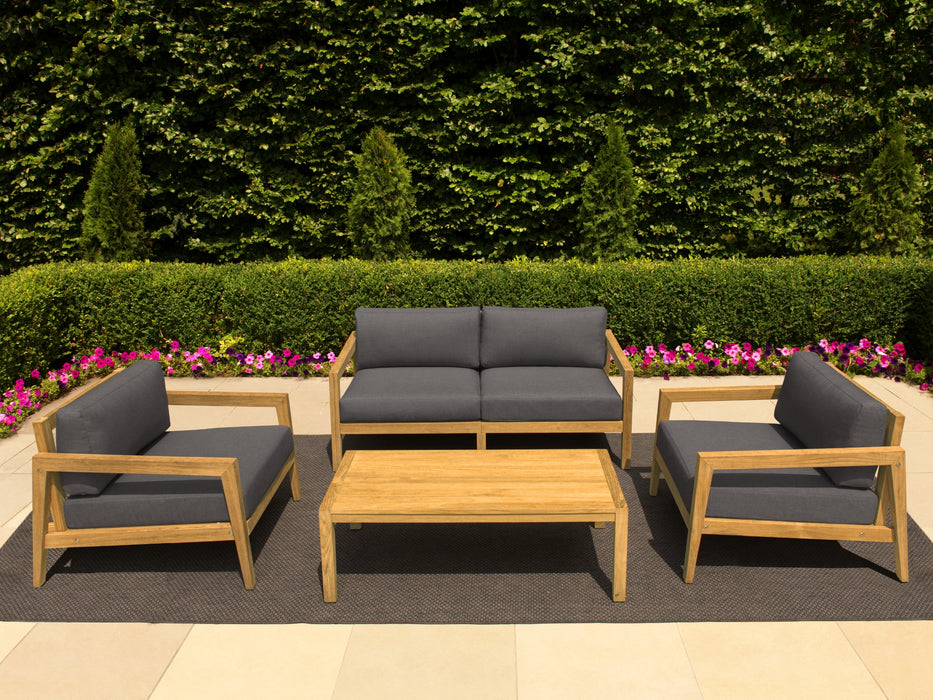 Rhodes Collection arranged in a garden setting with a large sofa, two armchairs, a coffee table, and an ottoman, all featuring grey cushions and wooden frames.