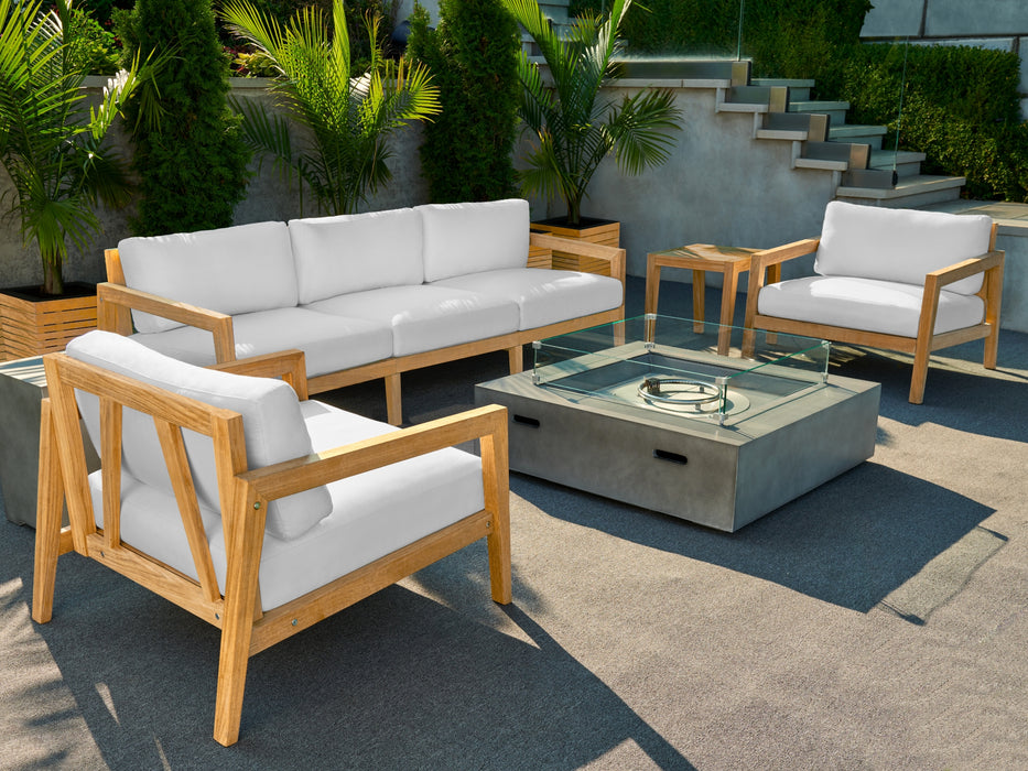 Rhodes Collection with a glass top fire table and side table, cushioned seats, and wooden frame on a grey outdoor rug with steps and greenery in the backdrop.