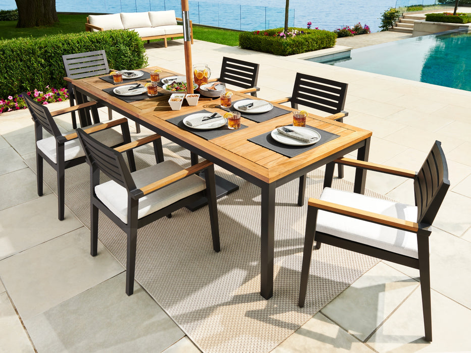 Rhodes dining set placed poolside, showcasing a full table setting with a view of a pool and garden.