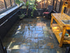 Interior of the Exaco Royal Victorian VI-34 greenhouse showing slate tiles and wooden potting bench with lush plants.