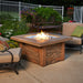 The Fire Pit Table lit with flames, with outdoor seating and decorative elements around it.