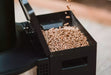 Close-up of wood pellets being loaded into the Solo Stove Tower Patio Heater for a cozy outdoor ambiance.