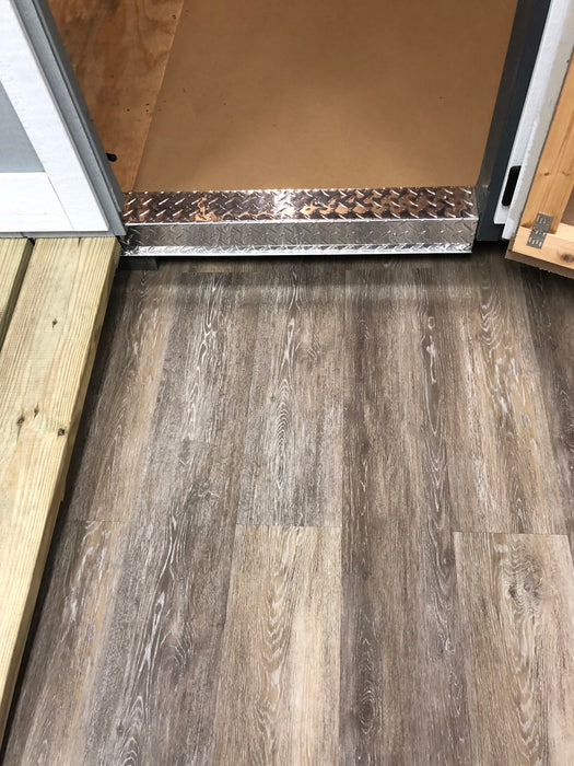 EzFit wooden ramp with diamond-patterned metal trim for seamless shed entry on laminate flooring.