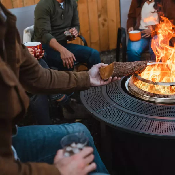 A man putting wood on Solo Stove Fire Pit with Surround.