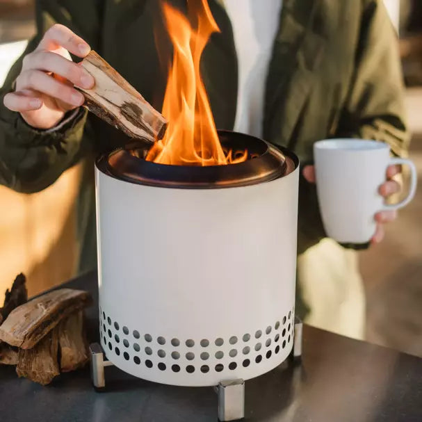 A person putting wood on Mesa Tabletop XL Fire Pit.