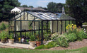 Grand and spacious Royal Victorian VI 46 Greenhouse by Exaco Janssens with a traditional peaked roof design, complemented by a beautifully landscaped garden with perennials and shrubbery.