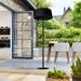  A modern electric standing heater is placed on a shaded patio next to sliding doors. 