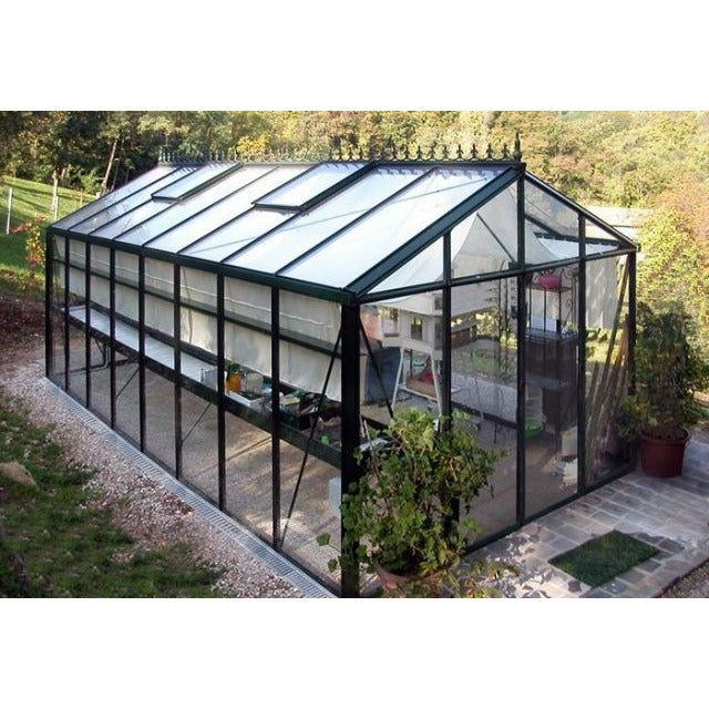 Graceful and sturdy structure of Exaco Janssens Royal Victorian VI 46 Greenhouse with its black framing and symmetrical glass panelling, offering a picturesque backdrop to a well-kept garden.