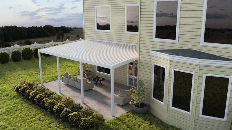 A top right side view of the Four Seasons Outdoor Living Solutions Optima Patio Cover installed against the wall of a house with 4 posts supporting its cover. There's 2 couches and a coffee table under the patio cover.