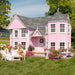 Tea party in front of a Little Cottage Company pink playhouse named Sara's Victorian Mansion Playhouse