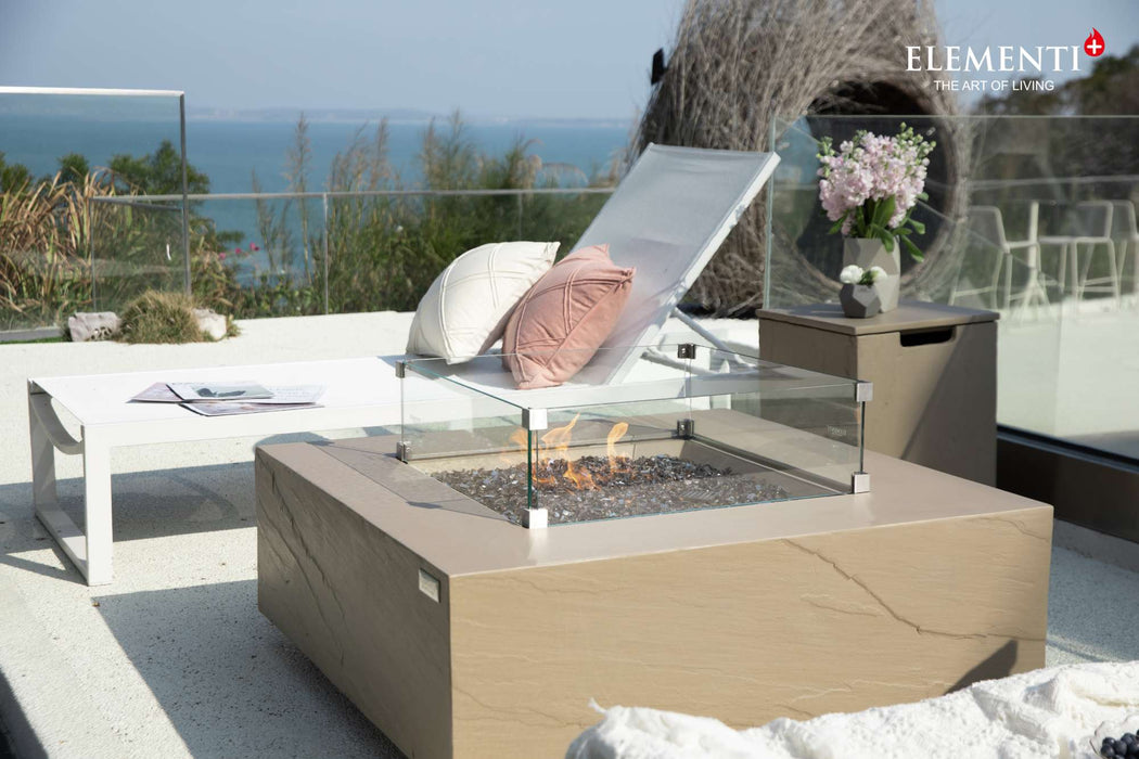 Sunlight yellow Uluru outdoor fire table with a wind shield, complemented by a white sunbed for a stylish and cozy atmosphere