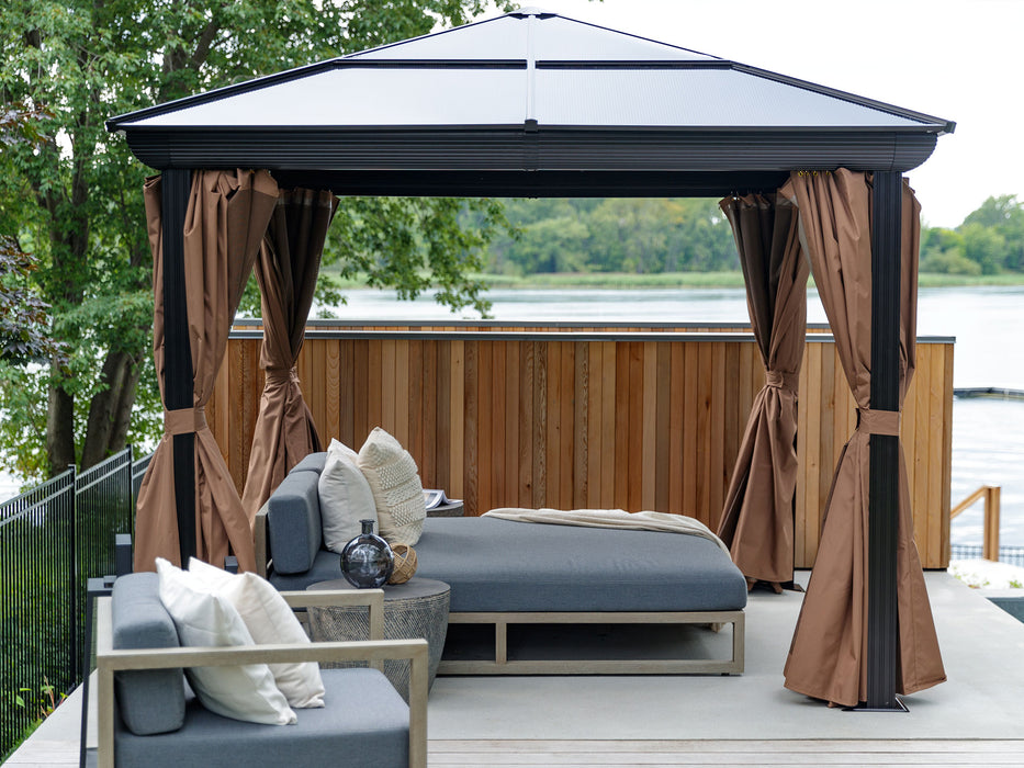 Venus Gazebo 10x10 on a deck with privacy curtains tied back to the posts, showing outdoor furniture inside and a view of the water in the background.