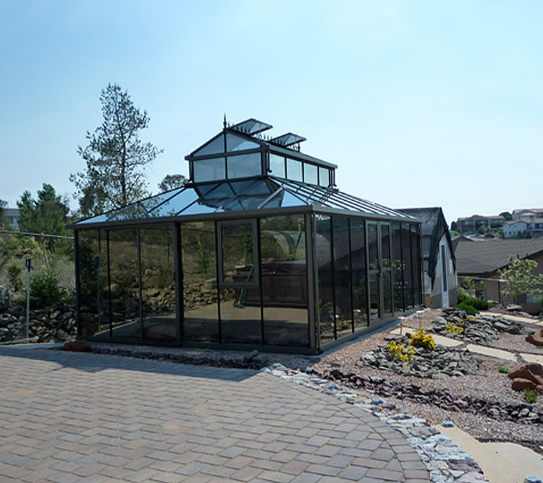 Modern 15x20 ft Victorian-style cathedral greenhouse with a pronounced large cupola, situated on a patterned brick foundation.