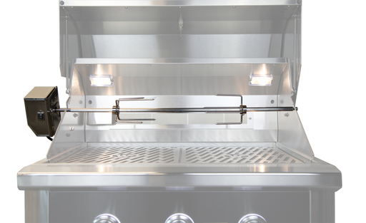 Wildfire Stainless steel rotisserie kit installed inside a grill, featuring a spit rod, motor attachment on the left, and two bright interior lights illuminating the cooking area.