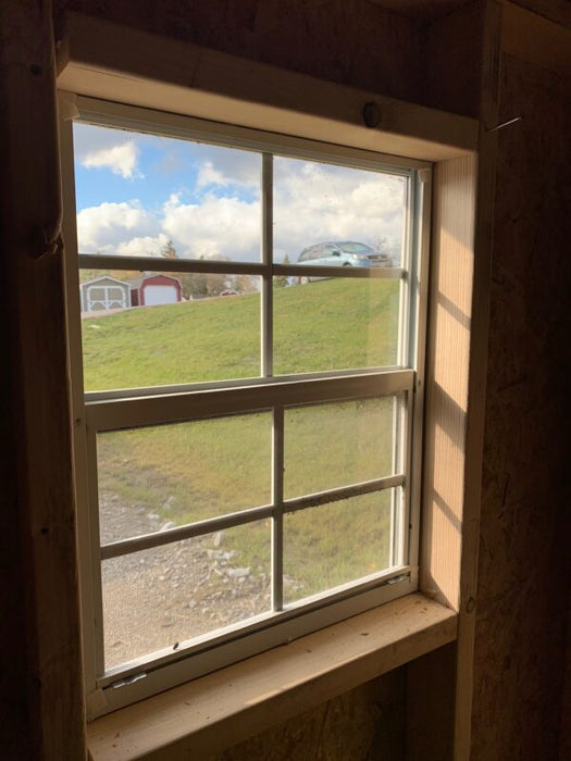 View from within the Classic Saltbox Shed looking out a window, providing a glimpse of the natural surroundings and the bright interior.