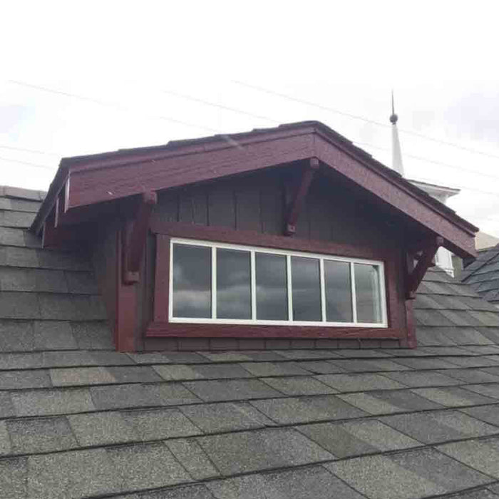 A view from outside the Craftsman Playhouse with Slide by Little Cottage Company, highlighting the quaint window that adds to its picturesque exterior