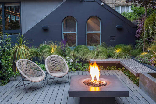 A wooden deck patio showcasing a central elevated Halo fire pit, providing a warm focal point for the outdoor seating area.