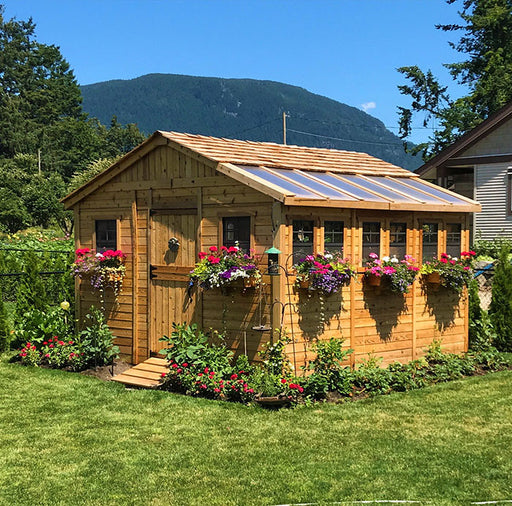 Idyllic cedar garden shed, 12x12, by Outdoor Living Today, with skylights and lush garden, set against a stunning mountain backdrop