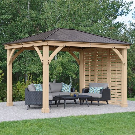 An elegant wooden gazebo equipped with Yardistry Meridian privacy walls, providing a secluded outdoor seating area with stylish wicker furniture and decorative cushions, set against a backdrop of lush trees.