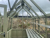 A contemporary garden setup featuring the Alton Cedar Structure Durham Greenhouse, seamlessly blending into its surroundings.