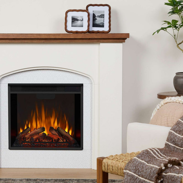 Real Flame Anika electric fireplace in living room close-up with faux tile surround, warm flame effect, wood mantel, framed photos, and cozy armchair with throw blanket beside it