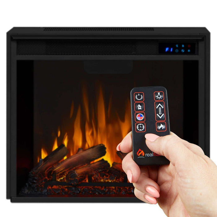 Hand holding Real Flame Anika remote control in front of lit electric fireplace insert displaying vivid orange flame effect with glowing log bed