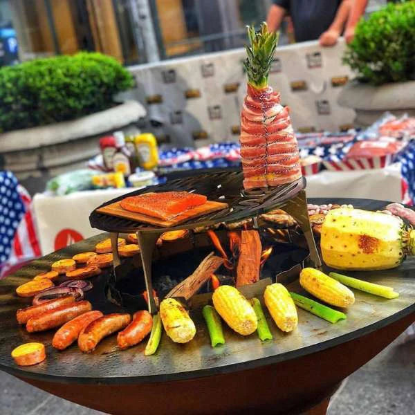 Casual outdoor dining scene featuring grilled sausages, corn, and vegetables on the Arteflame Classic Black Label 40-inch tall base grill.