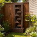 Vertical backyard cascade water fountain in textured rust finish, positioned near wooden fence and landscaped garden plants