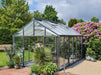 A sturdy livingten greenhouse frame without plants, featuring clear glass panels set on a gravel base.