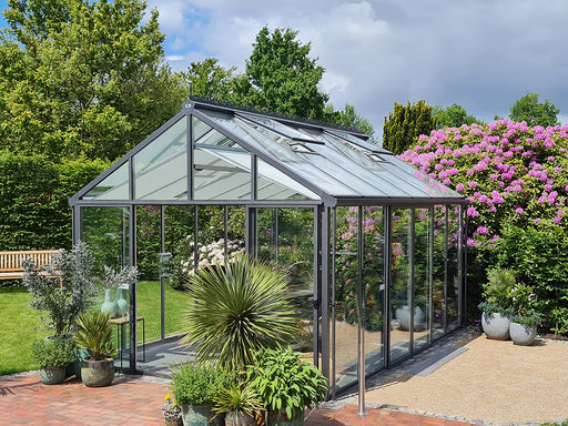 A sturdy livingten greenhouse frame without plants, featuring clear glass panels set on a gravel base.
