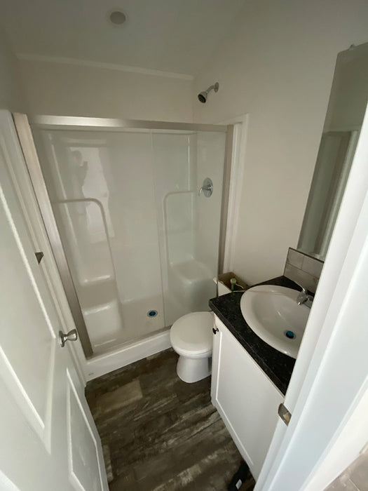 Interior of the bathroom in the Champion Home No Loft by Oasis Tiny Estates, equipped with modern fixtures and vinyl flooring.