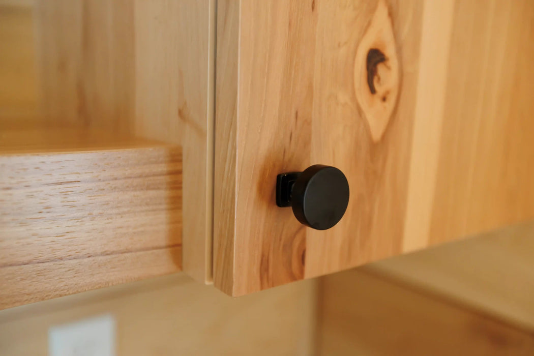 Close-up of a wooden cabinet with a black knob in the Oasis Tiny Estates Firestack Cabin