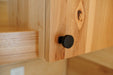 Close-up of a wooden cabinet with a black knob in the Oasis Tiny Estates Firestack Cabin