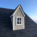 Close-up of a dormer window with white trim and gray shingles on the Little Cottage Co. Cape Cod Playhouse roof, highlighting charming architectural details.