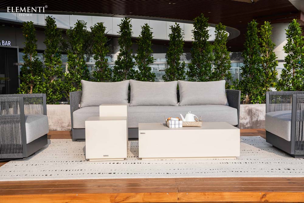 Full outdoor lounge setup featuring the Elementi Capri Collection sofa, matching chairs, and modern tables arranged stylishly on an open-air patio.